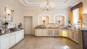 A spacious kitchen with white cabinetry, a central island, and a chandelier.