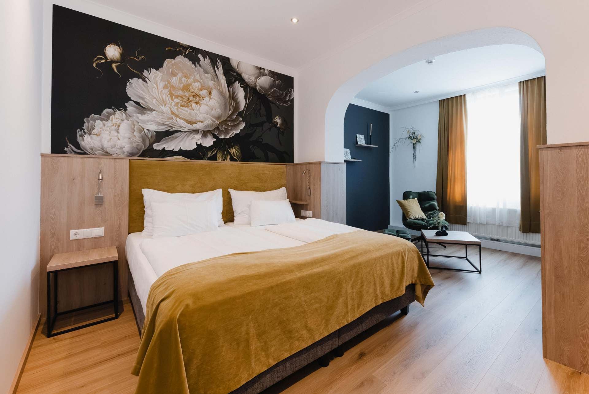 Ein Hotelzimmer mit einem großen Bett, einem Holz-Kopfteil, einem Bild an der Wand, einem Schreibtisch und einem Stuhl.