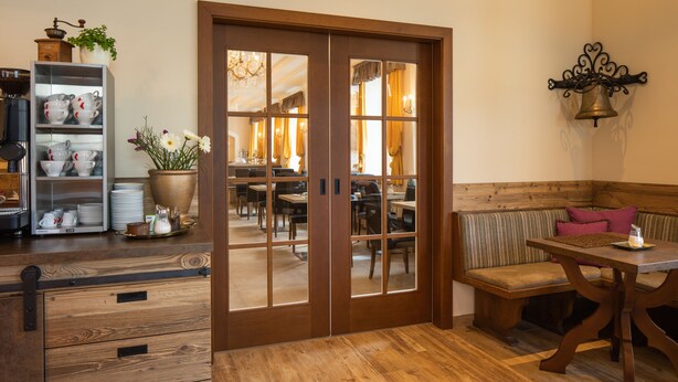 Un coin repas en bois avec un banc et une table, un meuble en bois avec des tiroirs, et une vue sur une salle à manger avec des tables et des chaises.