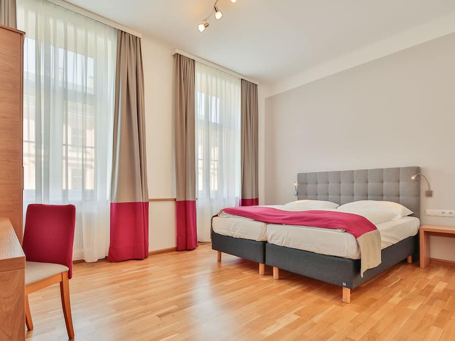 A modern bedroom with a double bed, a wooden desk, and a chair.