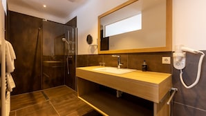 Une salle de bain moderne avec une douche à parois de verre, un meuble-lavabo en bois avec un lavabo blanc et un miroir au-dessus du lavabo.