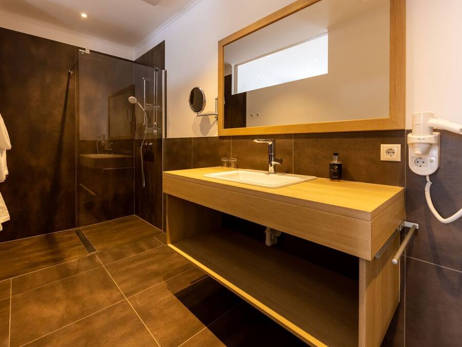 A modern bathroom with a glass-enclosed shower, a wooden vanity with a white sink, and a mirror above the sink.