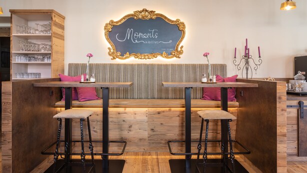 A cozy bar area with two stools, a wooden counter, and a chalkboard sign.