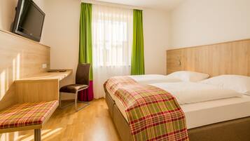 A hotel room with a bed, a desk, a chair, and a television.