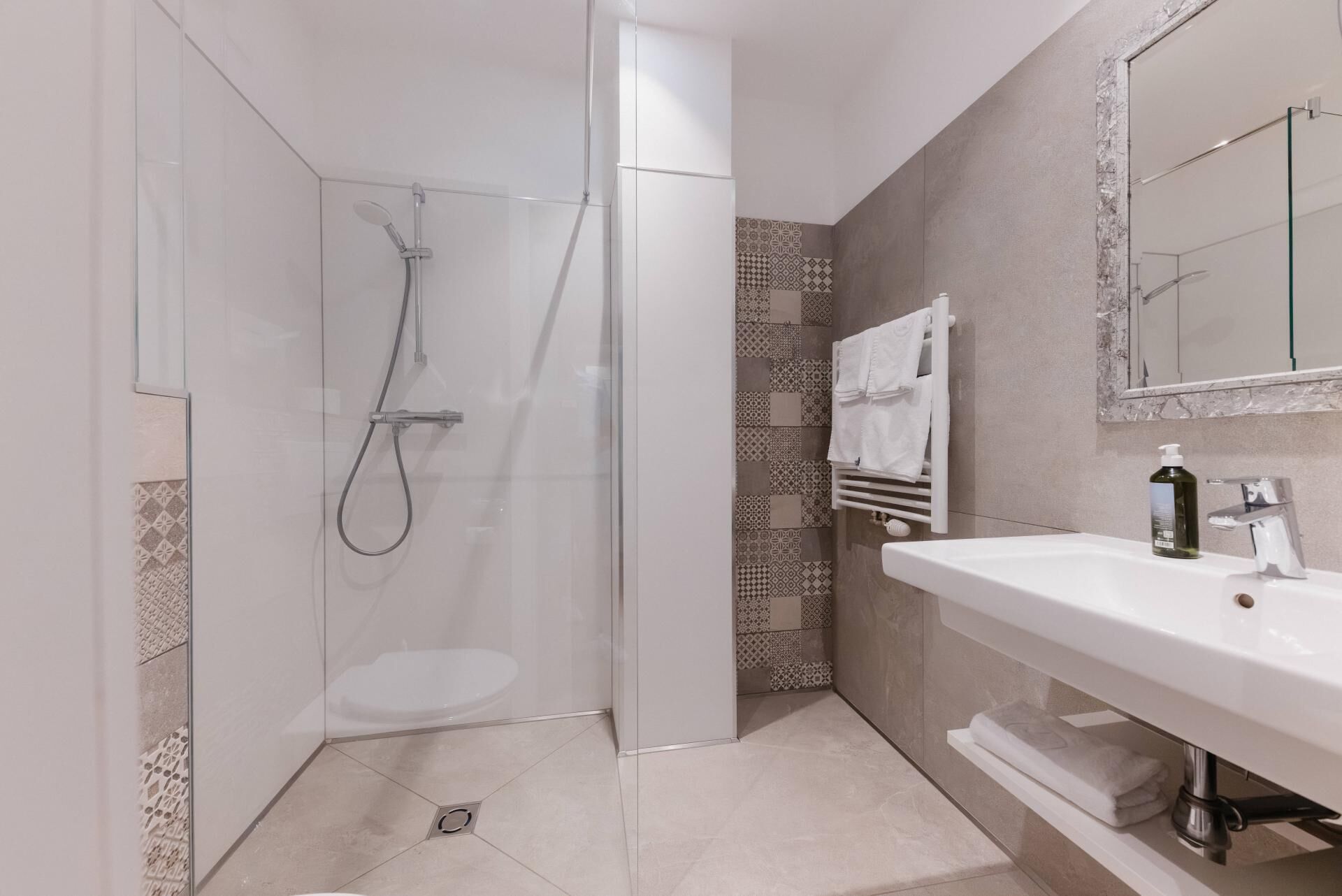A modern bathroom with a glass-enclosed shower, a white sink, and a mirror.