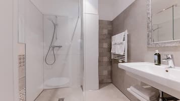 A modern bathroom with a glass-enclosed shower, a white sink, and a mirror.