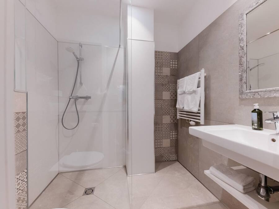 A modern bathroom with a glass-enclosed shower, a white sink, and a mirror.