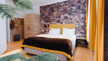 Een hotelkamer met een stenen muur, een bed met hoofdeinde, een houten kledingkast en een koffer.