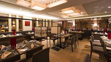 Un restaurante con varias mesas, sillas y una zona de bar.