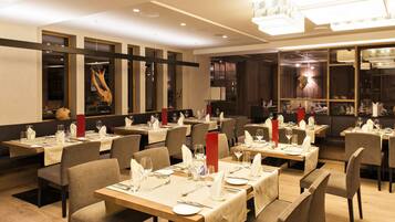 Un restaurante con varias mesas dispuestas para comer, con una decoración interior moderna, suelo de madera y mobiliario contemporáneo.