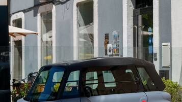 A compact car parked in front of a building with a balcony and a door.