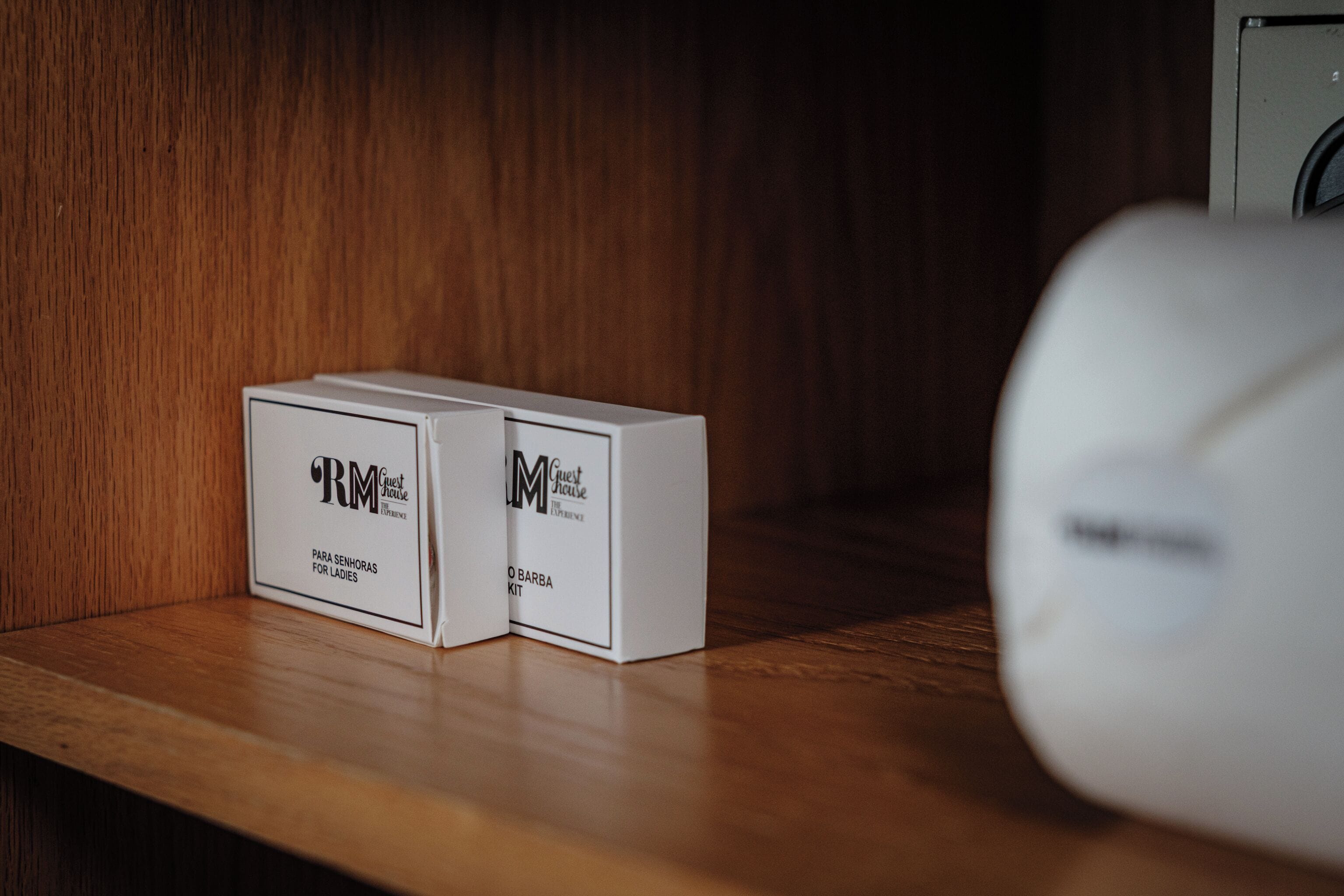 Dos cajas blancas con la etiqueta 'RM Guest House' sobre un estante de madera.