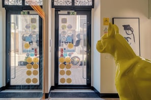 A hotel entrance with a yellow horse statue, a door with various stickers, and a framed artwork on the wall. - RM The Experience - Small Portuguese Hotels (Setubal)
