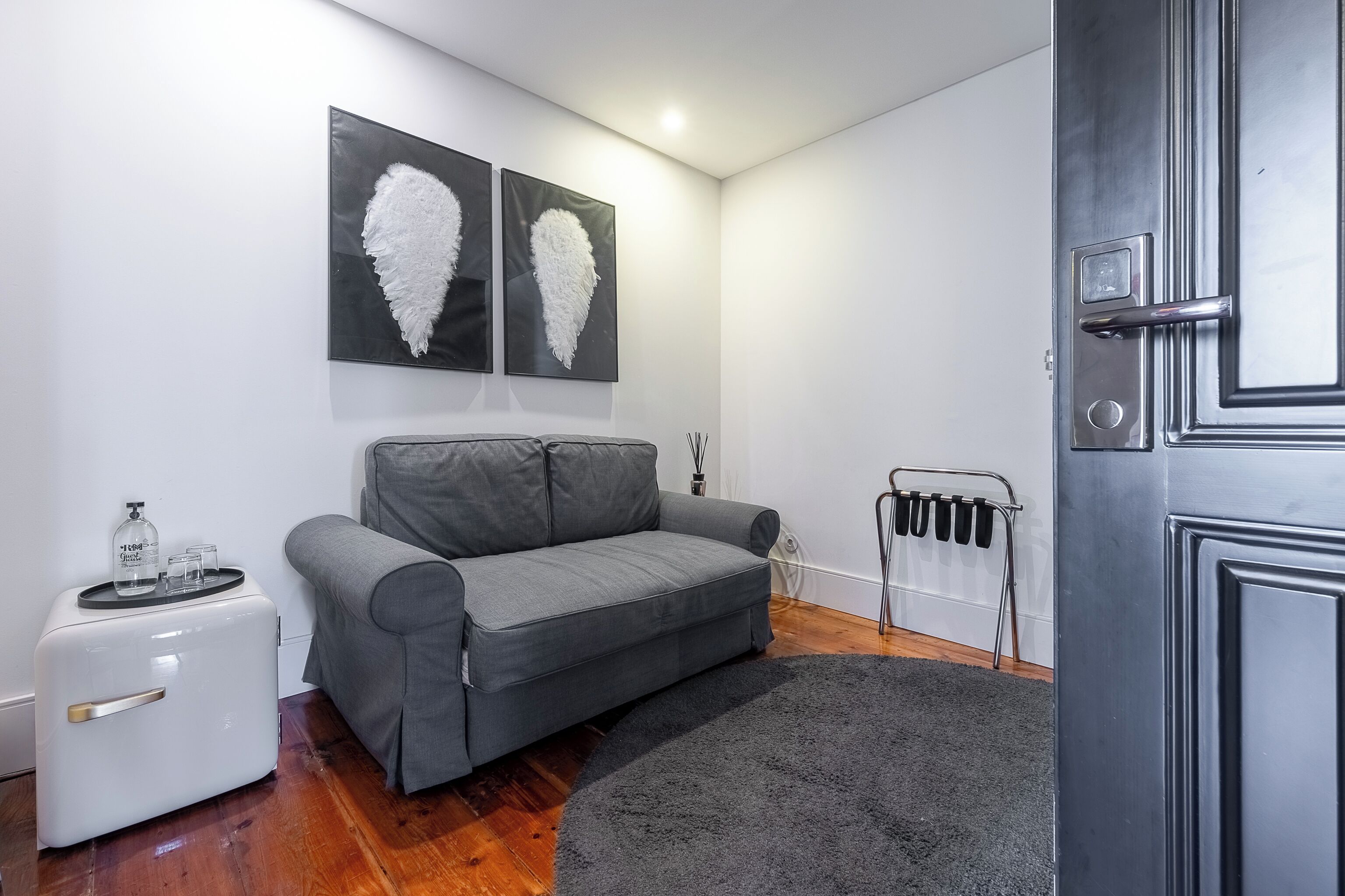 Ein modernes Wohnzimmer mit grauem Sofa, einem weißen Beistelltisch und zwei abstrakten Wandbildern.