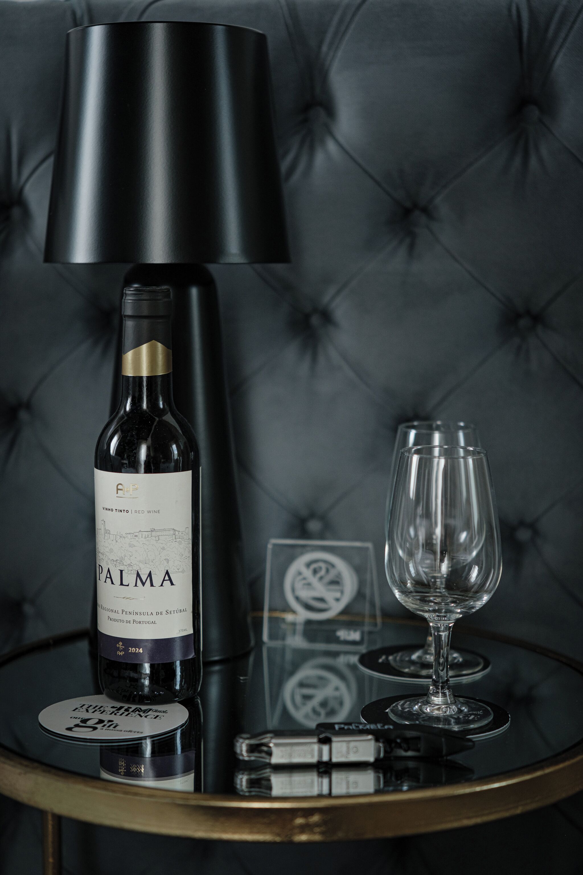 Una botella de vino, una copa de vino y una lámpara sobre una mesa.