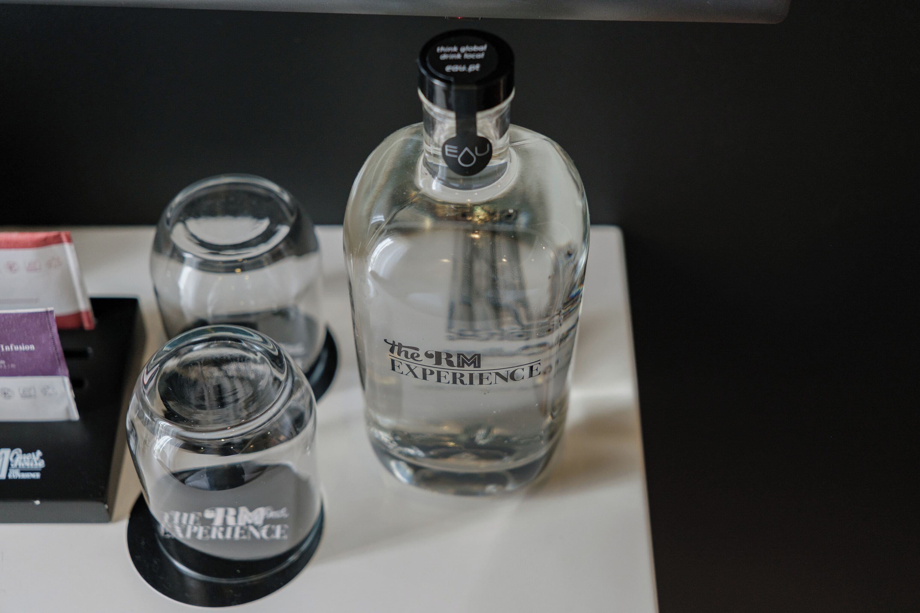 A bottle labeled 'The RM Experience' and two glasses on a table.