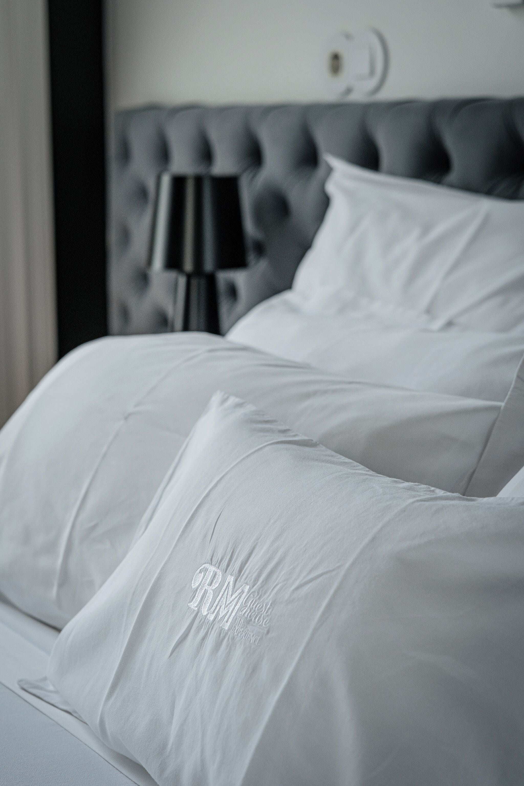 Cama com roupa de cama branca e cabeceira estofada.