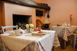 A dining area with two tables set for tea, each with a teapot, cups, and a vase of flowers. - Agriturismo Casale Bonaparte (Cellere)