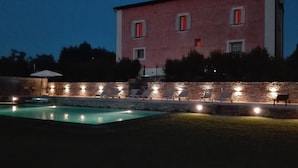 Una piscina con sillones de descanso y un muro de piedra.