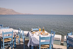 A seaside dining area with checkered tablecloths and blue chairs, overlooking the sea. - Kissamia - Self Check In Only - Next to Night Clubs (Kissamos)