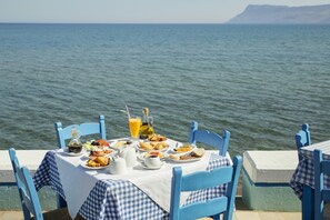 A table set with food and drinks by the sea, overlooking the water. - Kissamia - Self Check In Only - Next to Night Clubs (Kissamos)
