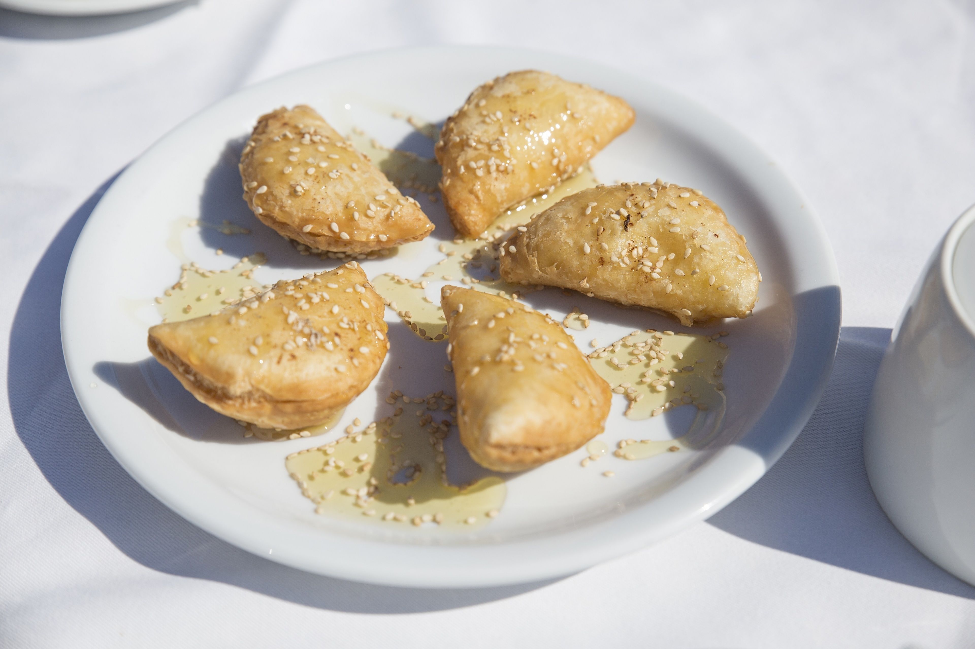 A plate of pastries with sesame seeds on a white plate.
