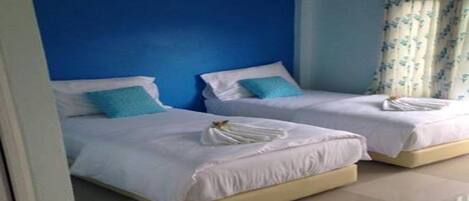 A hotel room with two beds, each with white bedding and a blue pillow.