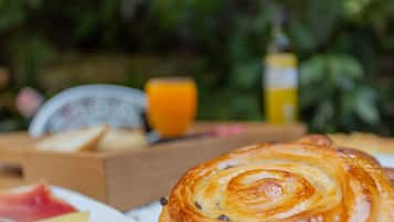Desayuno con pasteles, un vaso de jugo de naranja y una botella de jugo.