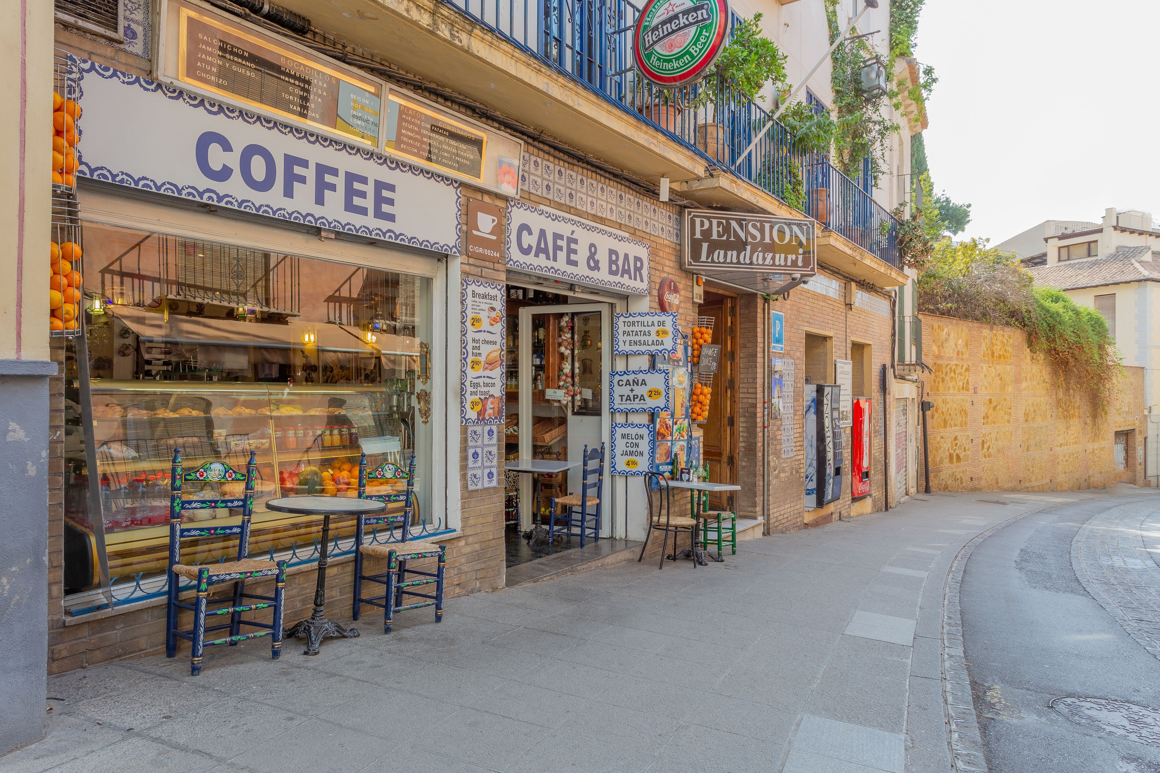 Une vue de rue avec un café, un bar-café et une petite pension.