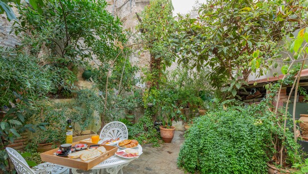 An outdoor dining area with a table set for two, surrounded by potted plants and a stone wall. - Pensión Landazuri (Granada)