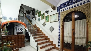 A staircase with a wooden handrail, a reception desk, and a patterned floor. - Pensión Landazuri (Granada)