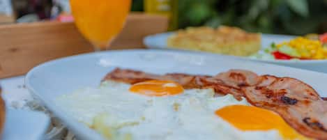 Un desayuno con huevos, tocino y un vaso de jugo de naranja sobre una mesa.