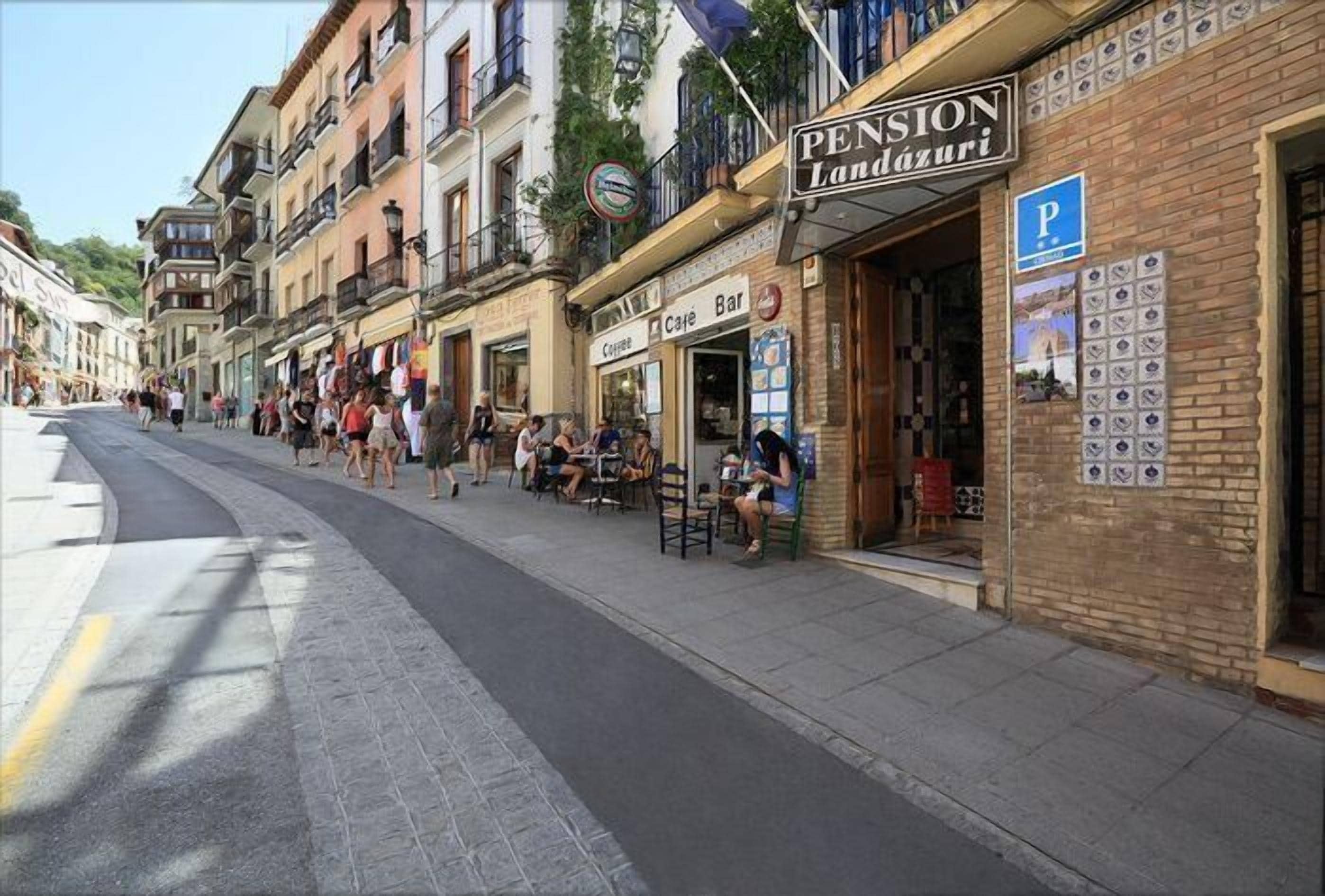 Eine Straße mit Außenplätzen eines Cafés oder einer Bar namens 'Café Bar'.