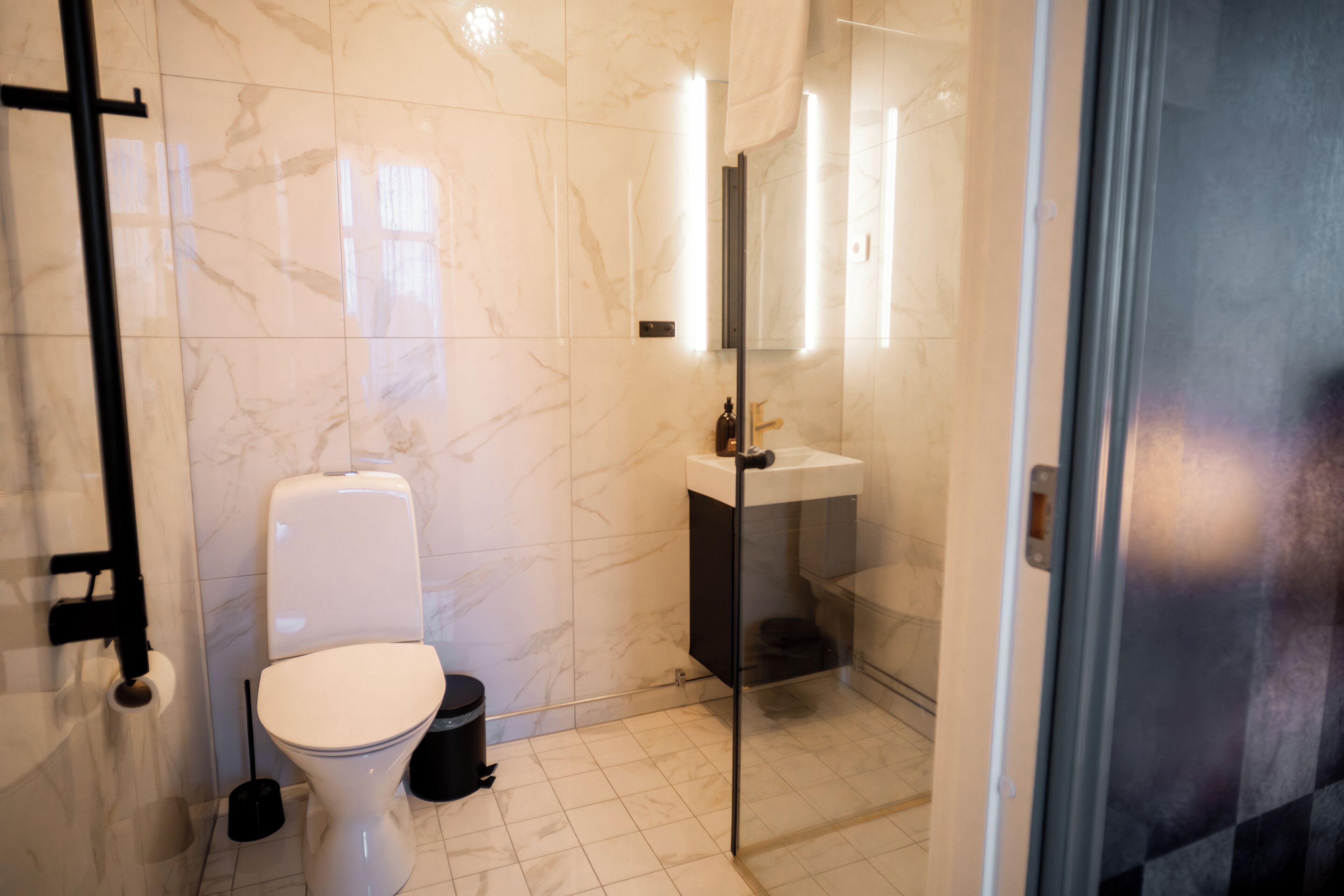 A modern bathroom with a toilet, sink, and glass shower enclosure.