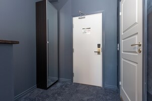 Un pasillo con una puerta blanca, una puerta de madera oscura y un pequeño estante.