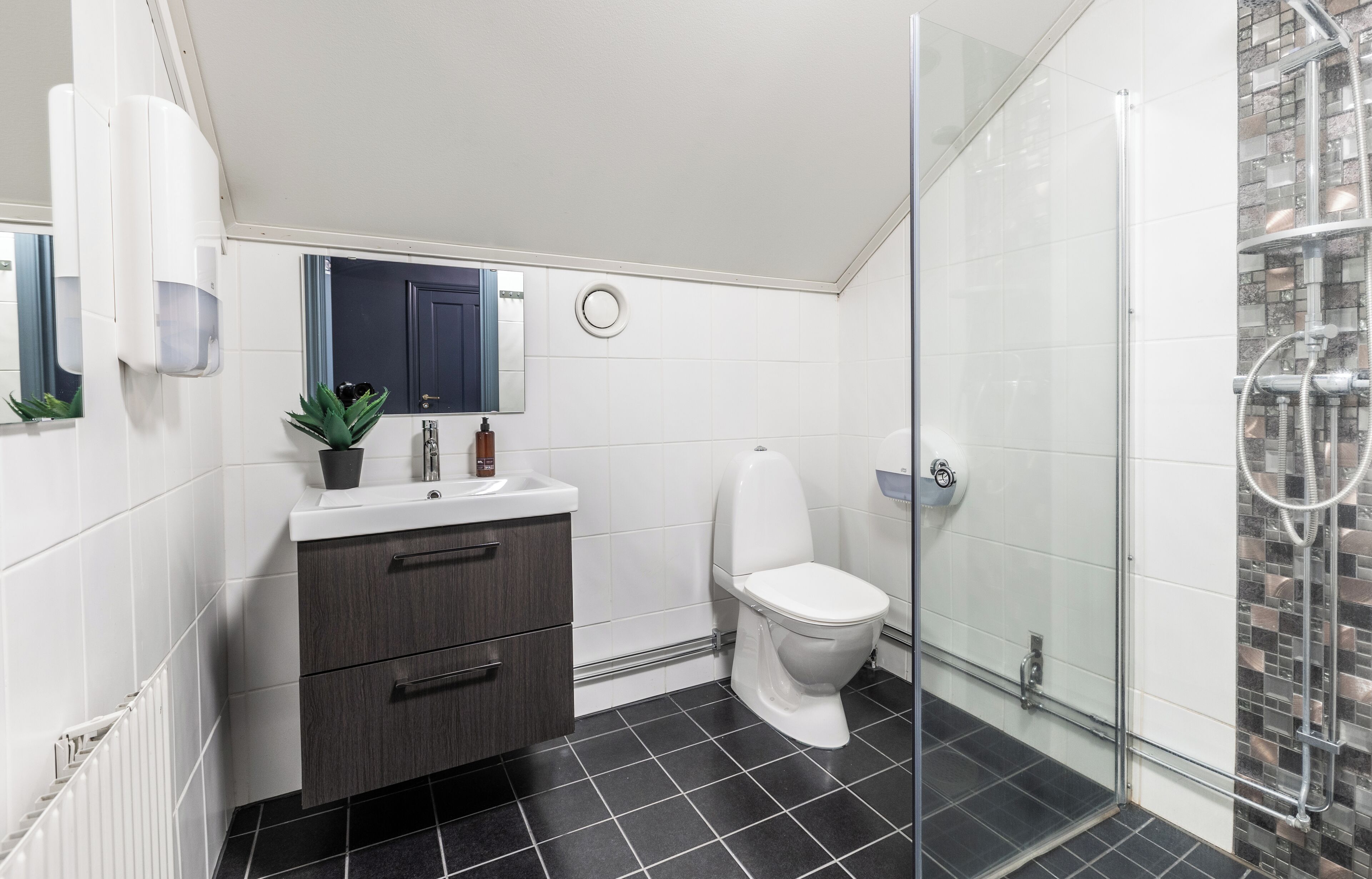 Un baño moderno con cabina de ducha de vidrio, inodoro blanco y tocador de madera oscura con espejo.