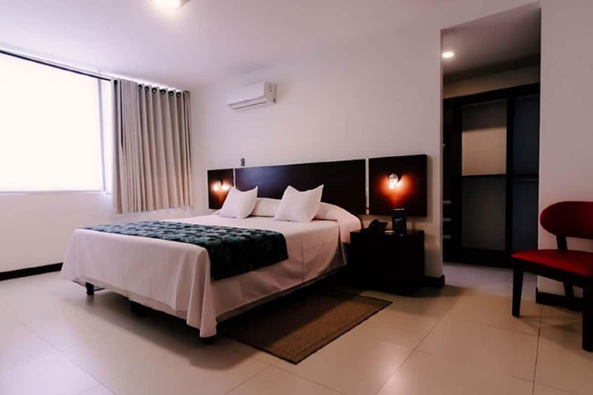 Un hotel moderno con cama, mesitas de noche, una silla y vistas al exterior.