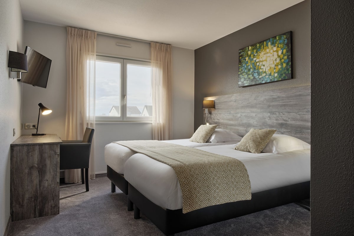 Una habitación de hotel moderna con una cama grande, un escritorio y un televisor montado en la pared.