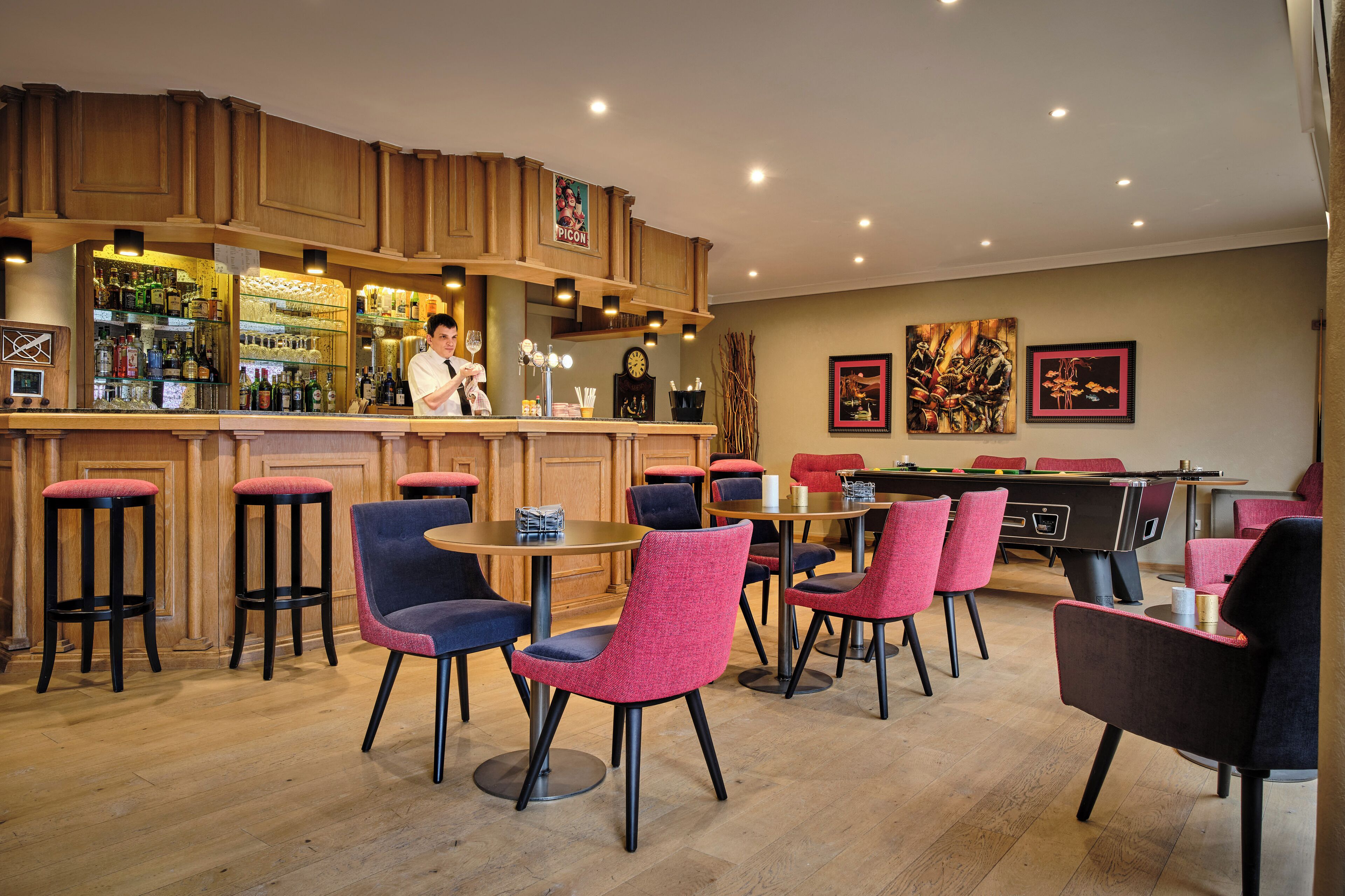 A bar area with stools, tables, and a pool table.