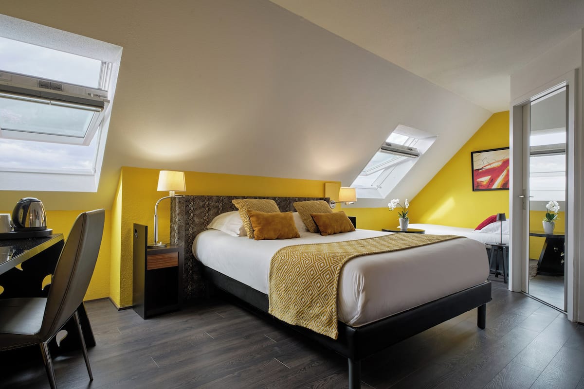 Un dormitorio moderno con tragaluz, una cama con colcha estampada, un escritorio con lámpara y una silla.