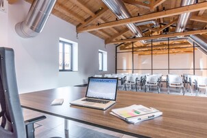 Una sala de conferencias moderna con techo de madera, una computadora portátil sobre una mesa y una libreta.