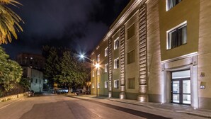 A street view at night with a building featuring a large entrance and a well-lit facade. - Camplus Palermo (Palermo)