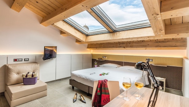 A hotel room with a skylight, a bed, a desk with glasses of wine, and a small table with a handbag. - Camplus Palermo (Palermo)