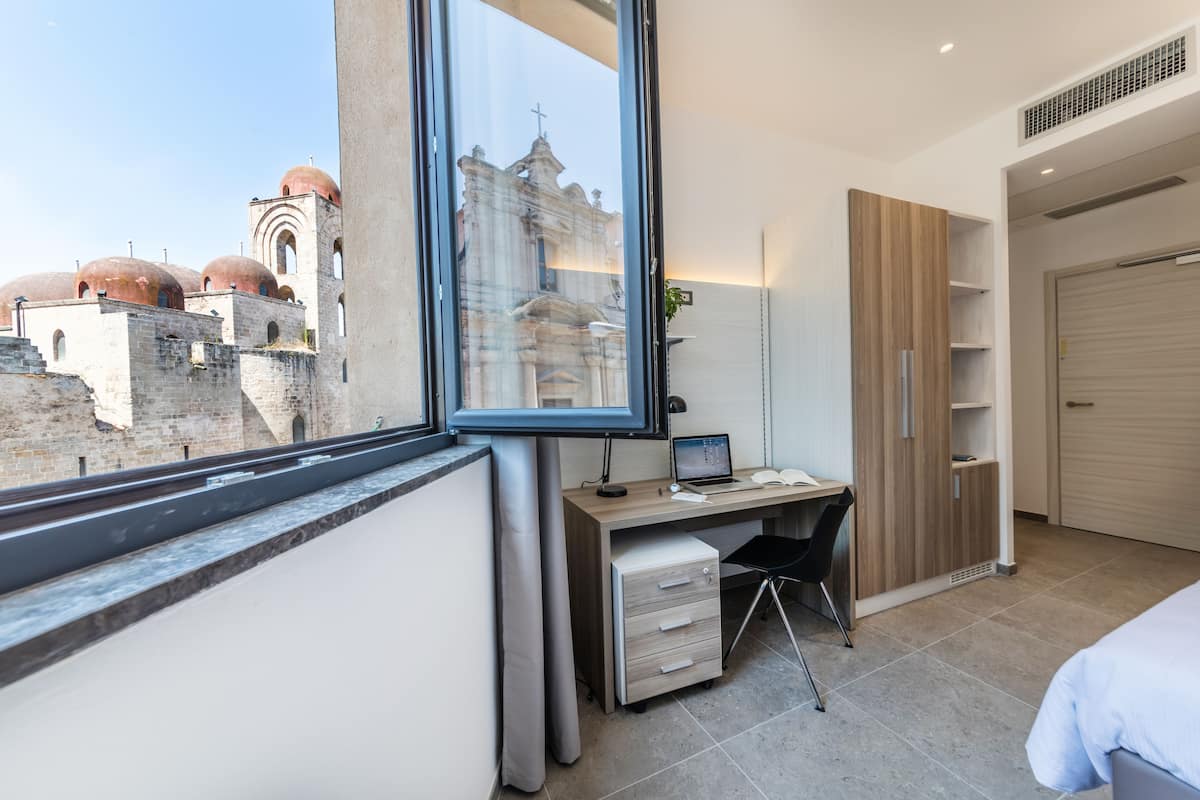 Une chambre moderne avec une grande fenêtre, un bureau et une armoire.