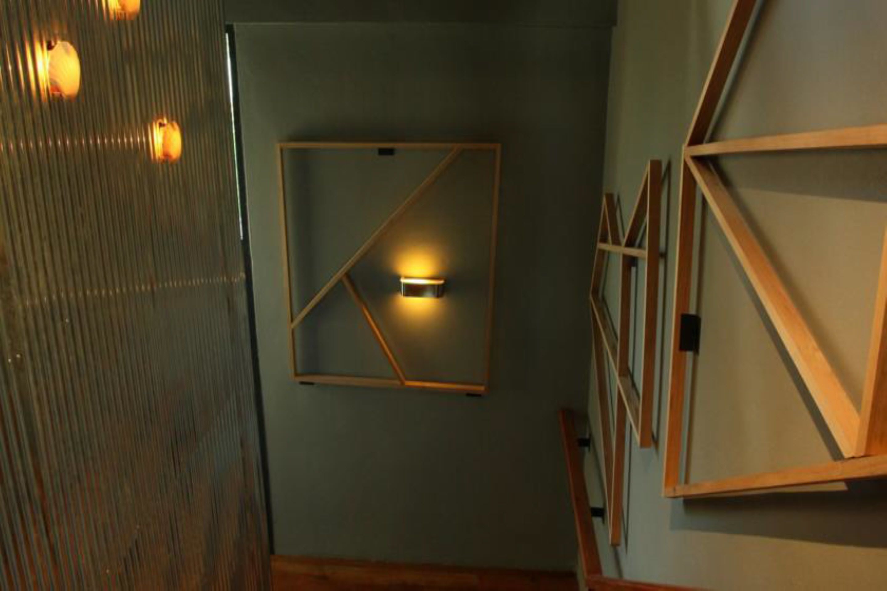 Una habitación con un diseño geométrico en la pared, una obra de arte enmarcada y suelo de madera.