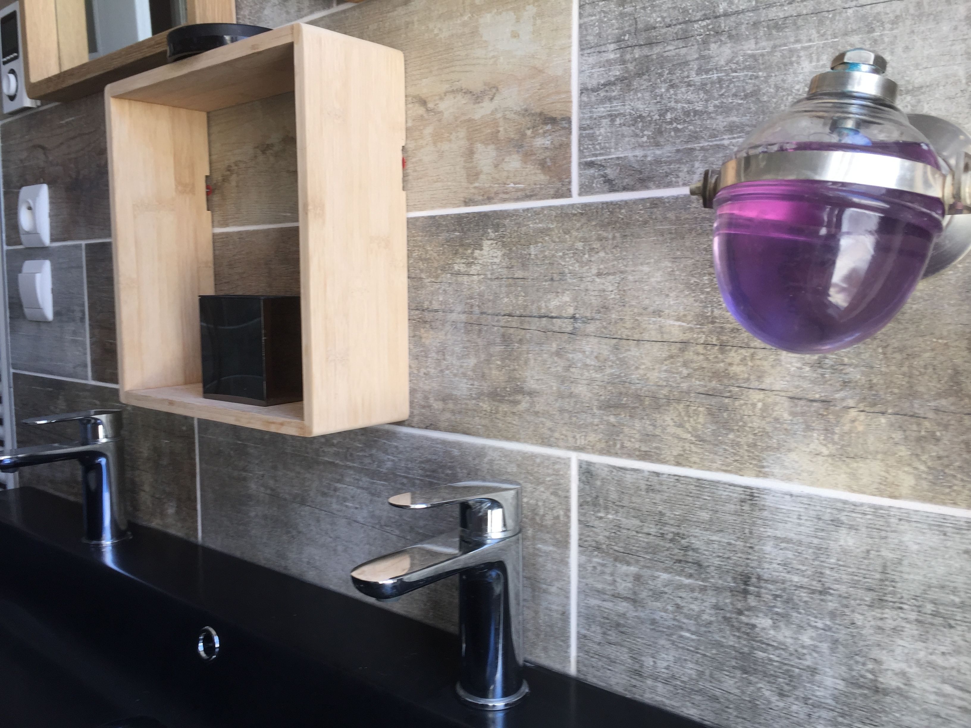 Une salle de bain avec deux lavabos, un meuble à pharmacie en bois et un luminaire violet.