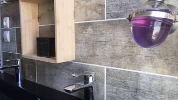 Une salle de bain avec deux lavabos, un meuble à pharmacie en bois et un luminaire violet.