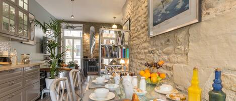 A cozy dining area with a stone wall, a bookshelf, and a table set with food and drinks.