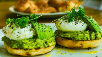 Two open-faced sandwiches with avocado and poached eggs on a plate.