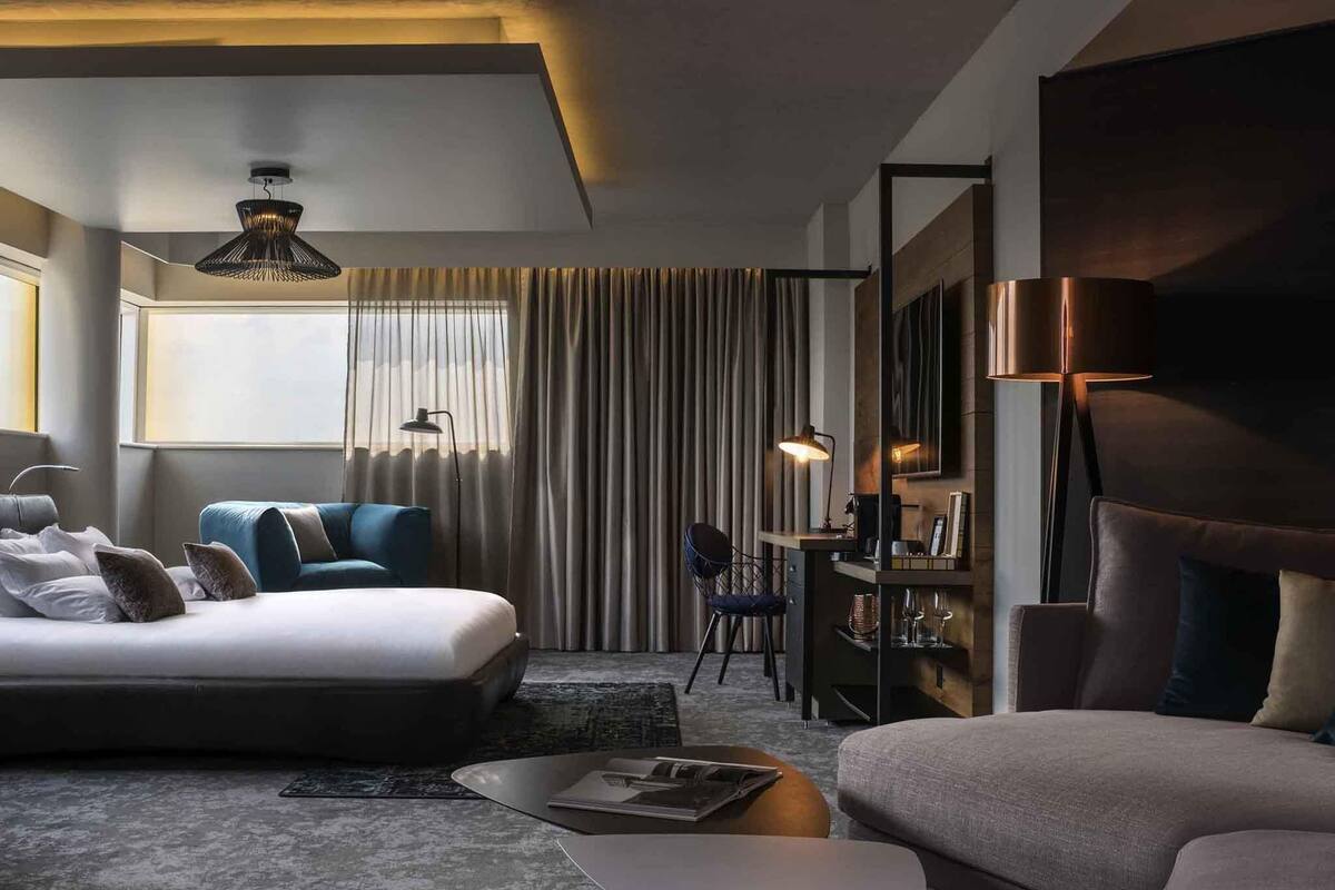 Une chambre d’hôtel moderne dotée d’un grand lit, d’un canapé, d’un bureau et d’un coin repas.